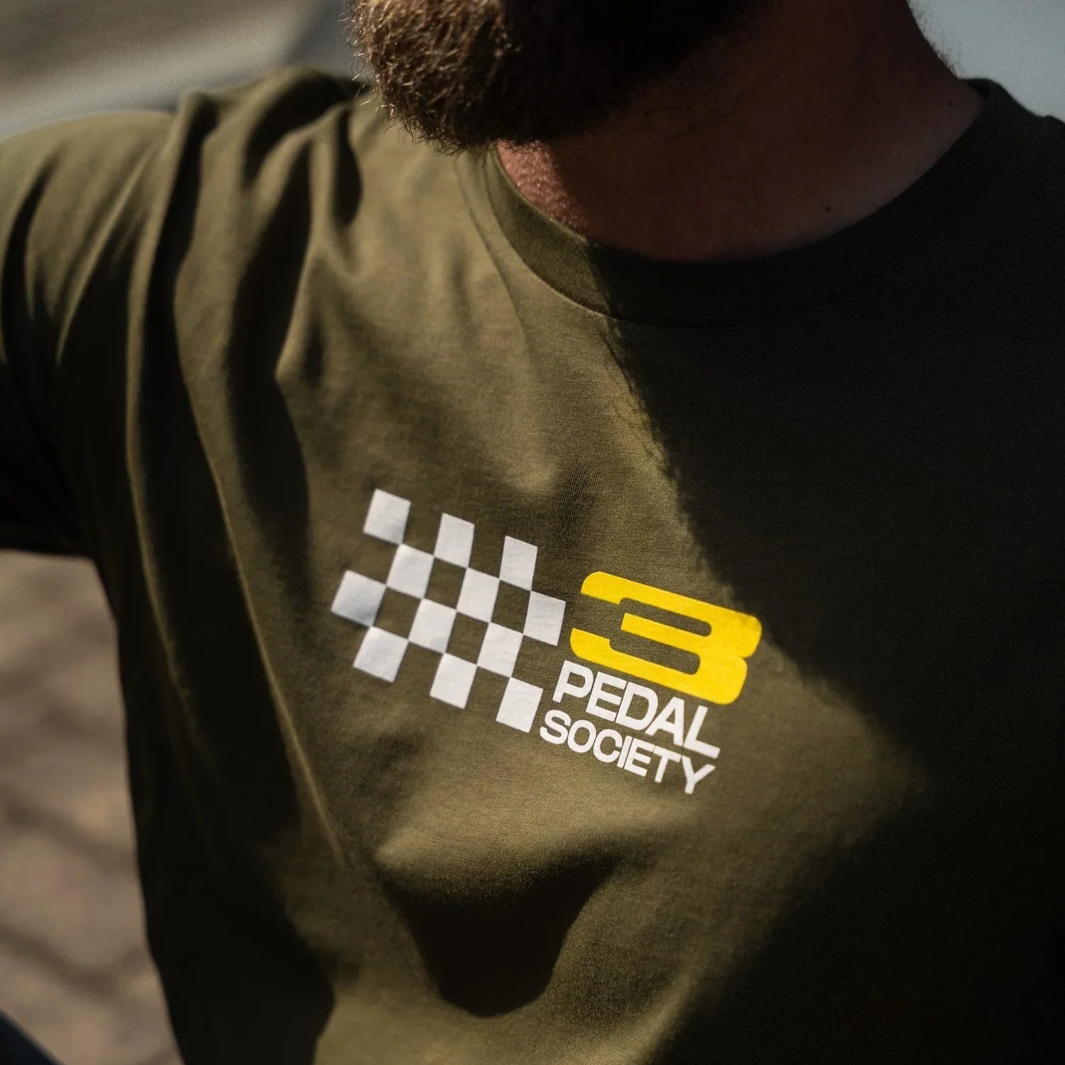 Person wearing a green t-shirt with 'Pedal Society' logo
