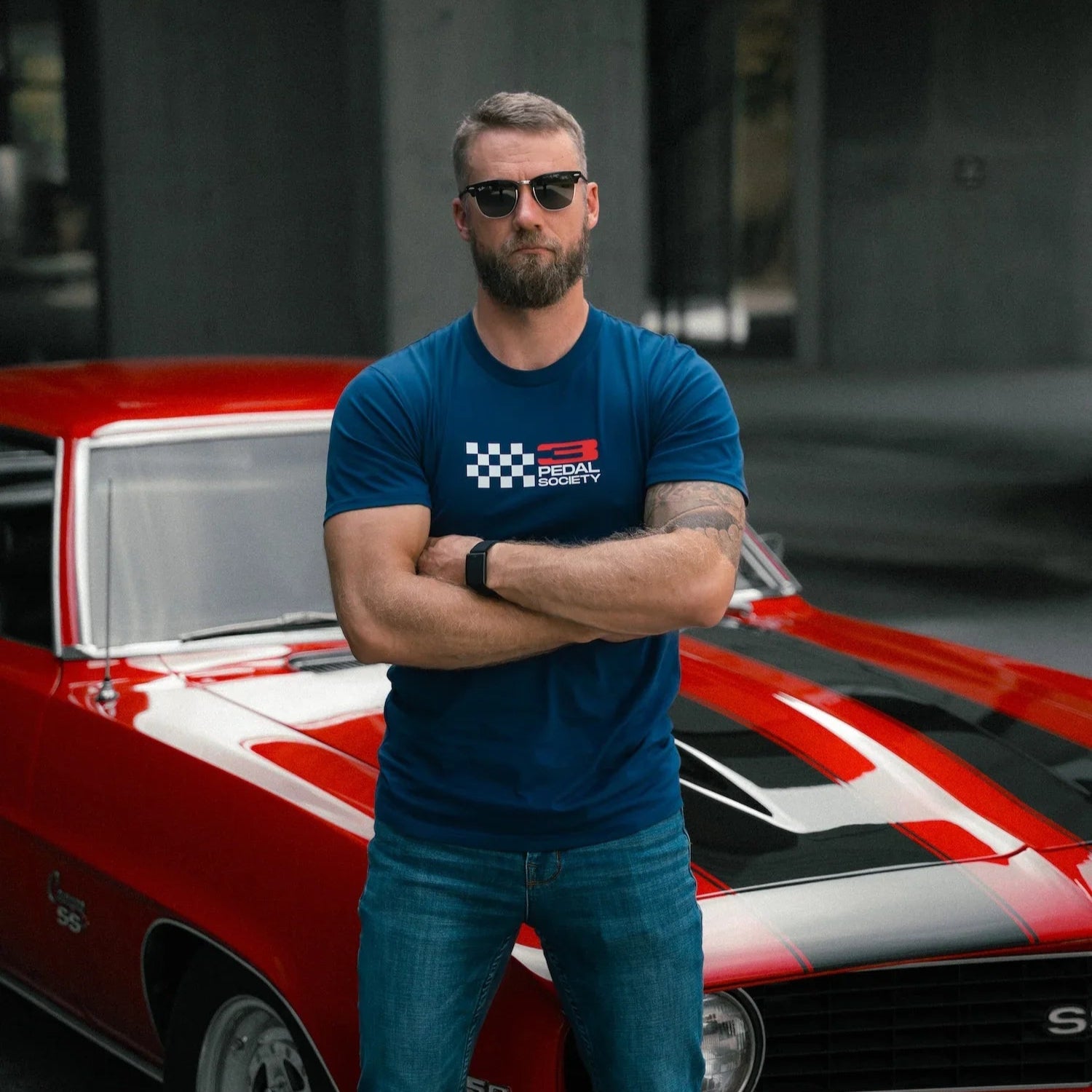 Man in a blue t-shirt standing in front of a red and white car
