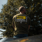 Man wearing a '3 Pedal Society' t-shirt standing outdoors with trees in the background