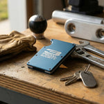 Blue cardholder with '3 Pedal Society' branding on a wooden surface with tools and keys.