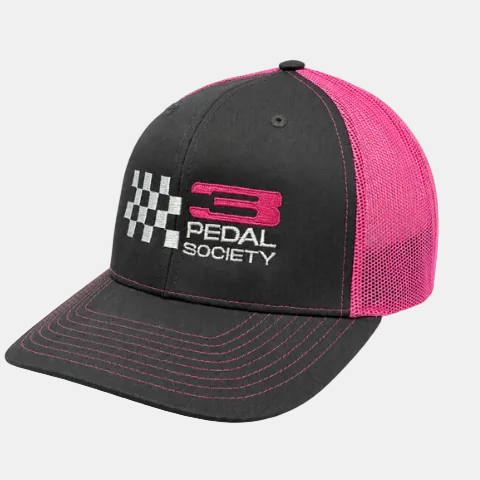 A black and pink trucker-style baseball cap with a curved brim, featuring a pink and white embroidered '3 PEDAL SOCIETY' logo on the front, alongside a checkered flag graphic. The cap has a black front panel, a pink mesh back, and pink contrast stitching on the brim.