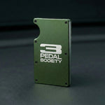 Green metal wallet with '3 Pedal Society' logo on a dark background