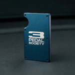 Blue metal bracket with '3 Pedal Society' logo on a dark background