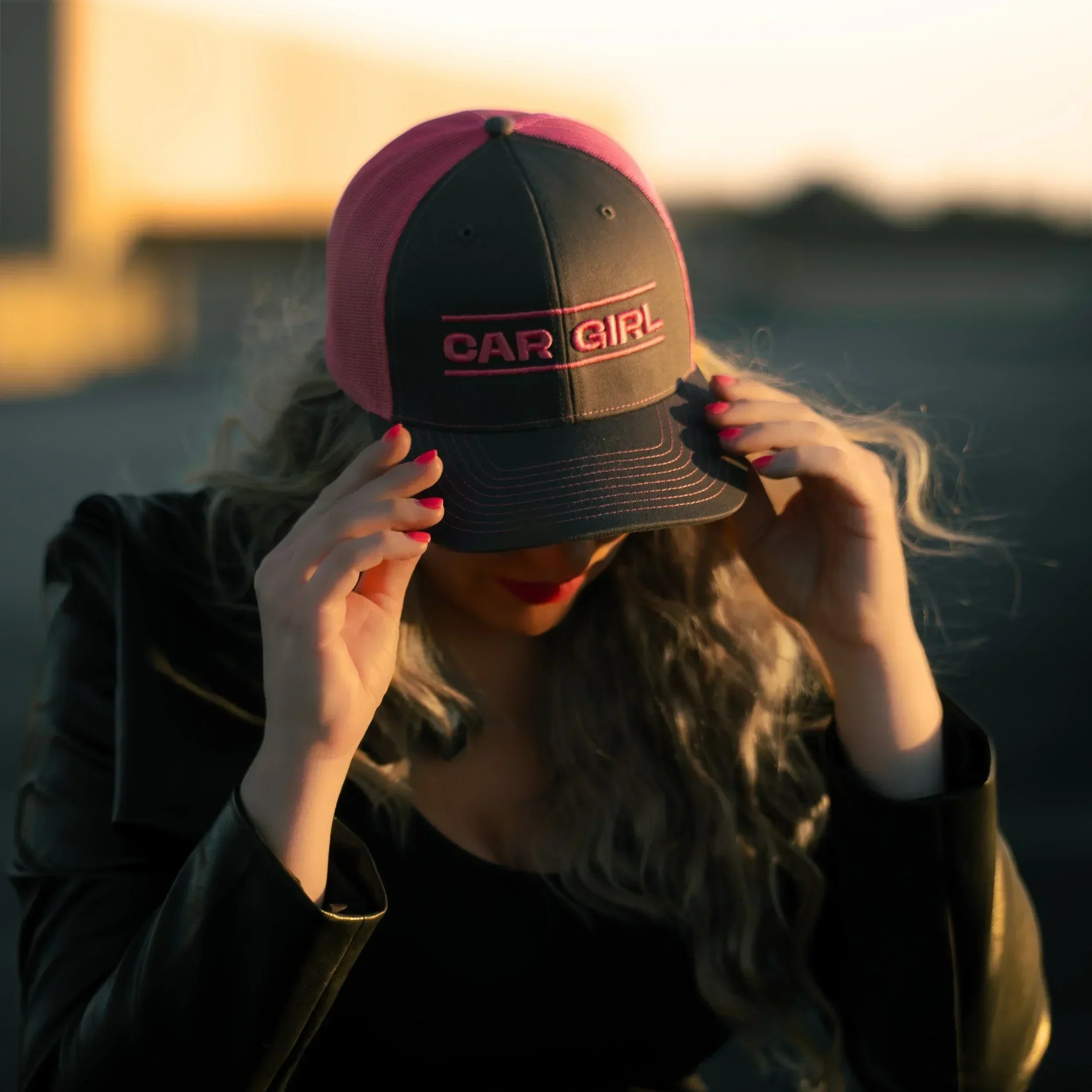 Person wearing a cap with 'CAR GIRL' text against a blurred background
