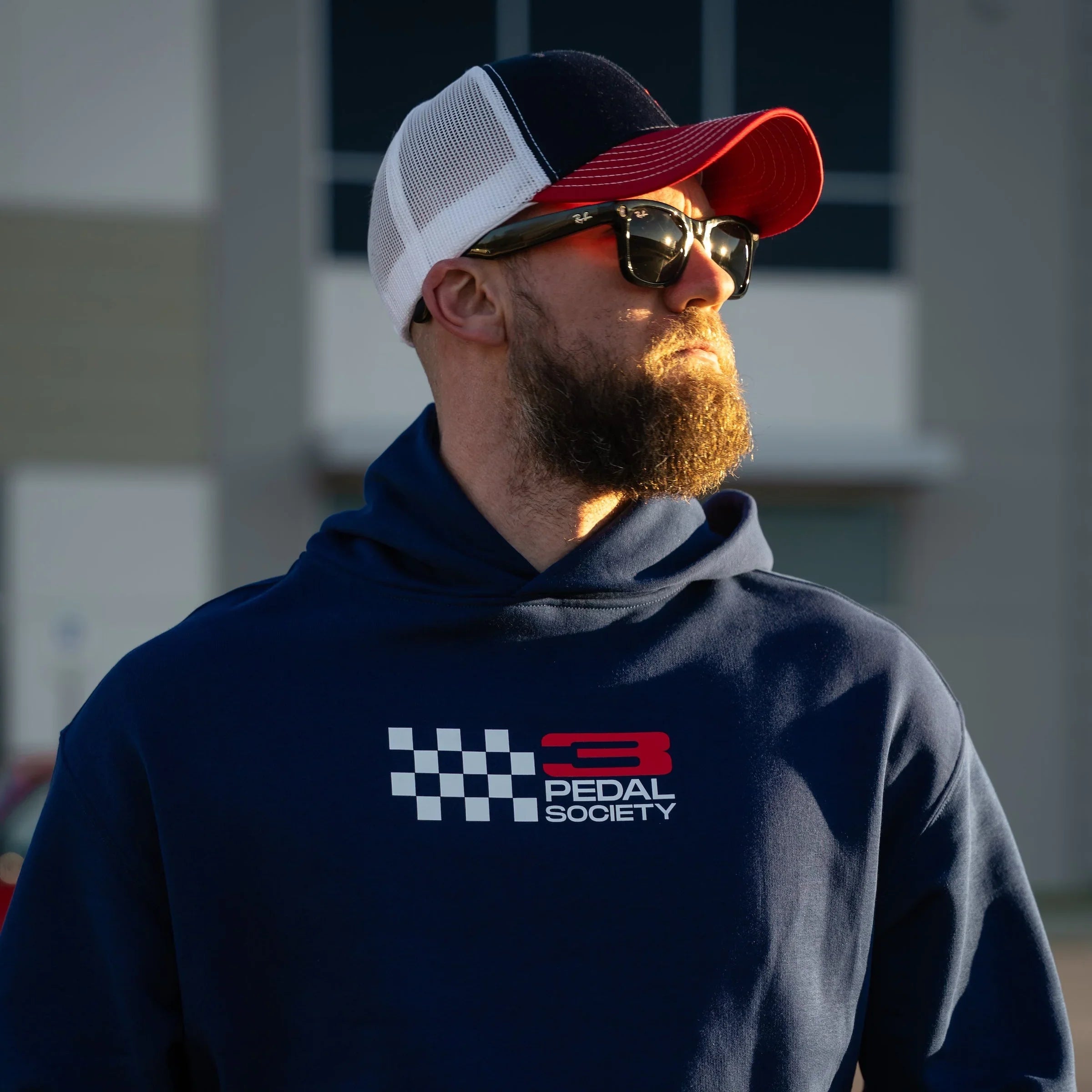 Man wearing a navy hoodie with a logo and text, standing outdoors.