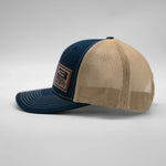 Two-tone blue and beige cap with mesh back on a light gray background