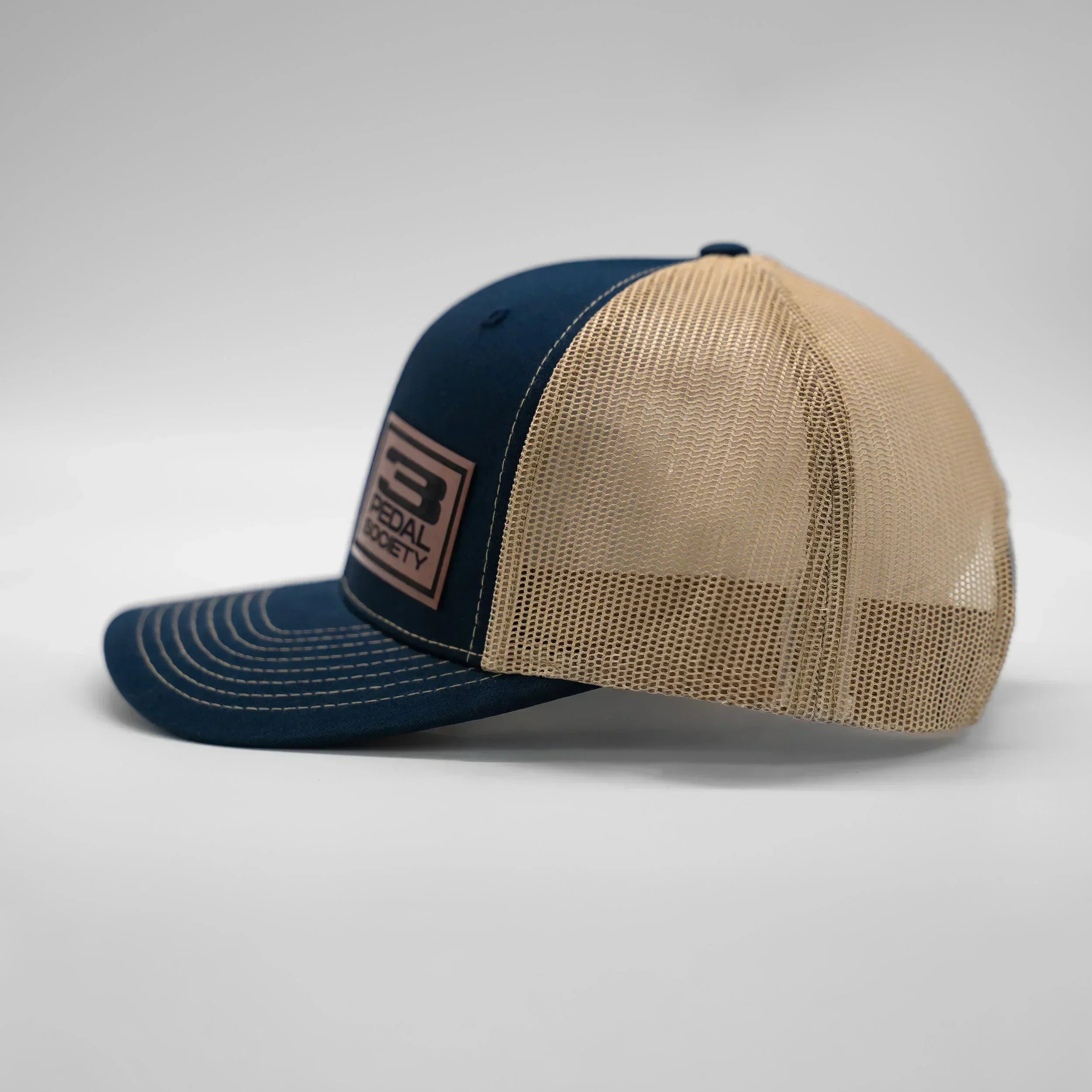 Two-tone blue and beige cap with mesh back on a light gray background