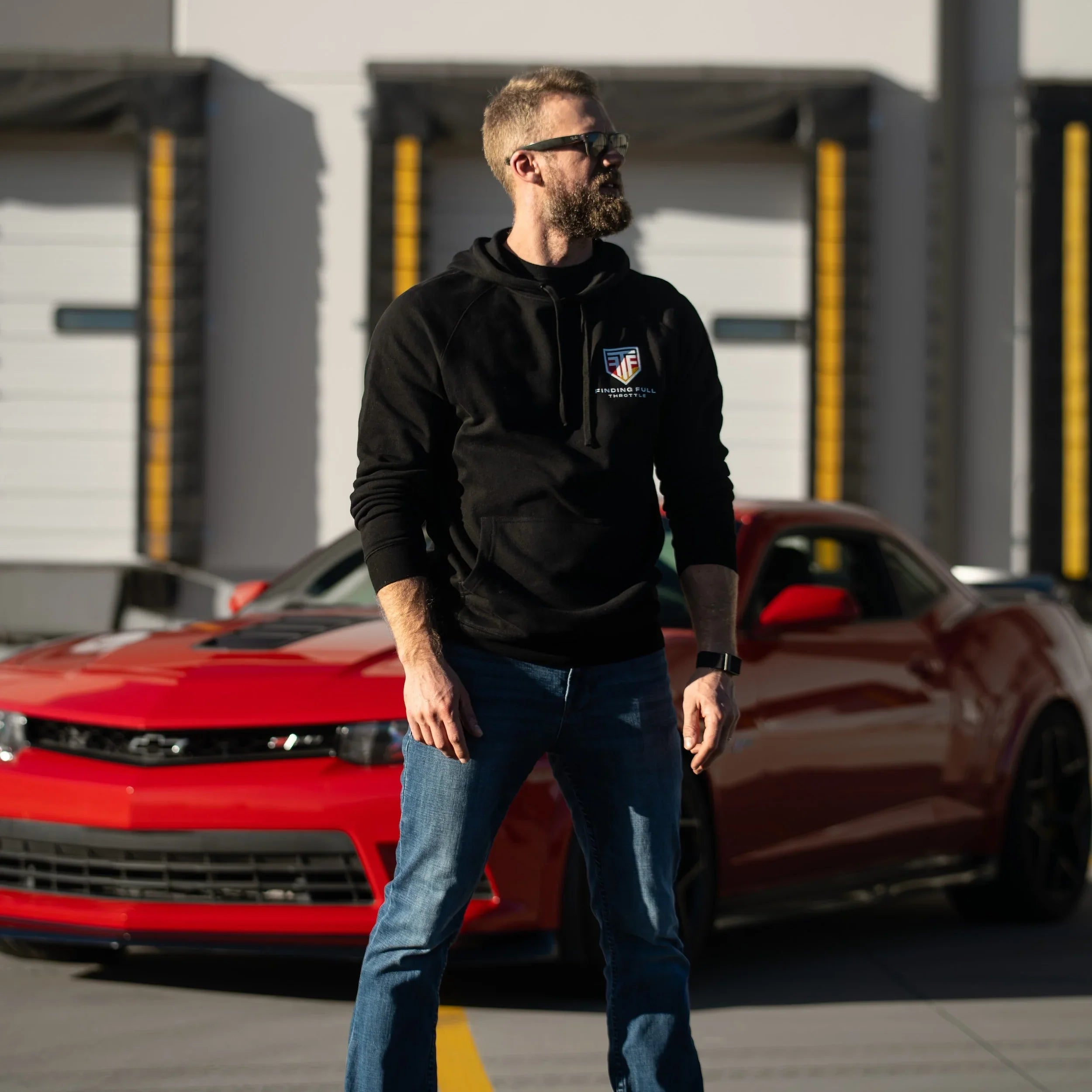 Man standing in front of a red car with a blurred background