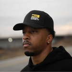Man wearing a black 3 Pedal Society hat with a logo against a blurred background