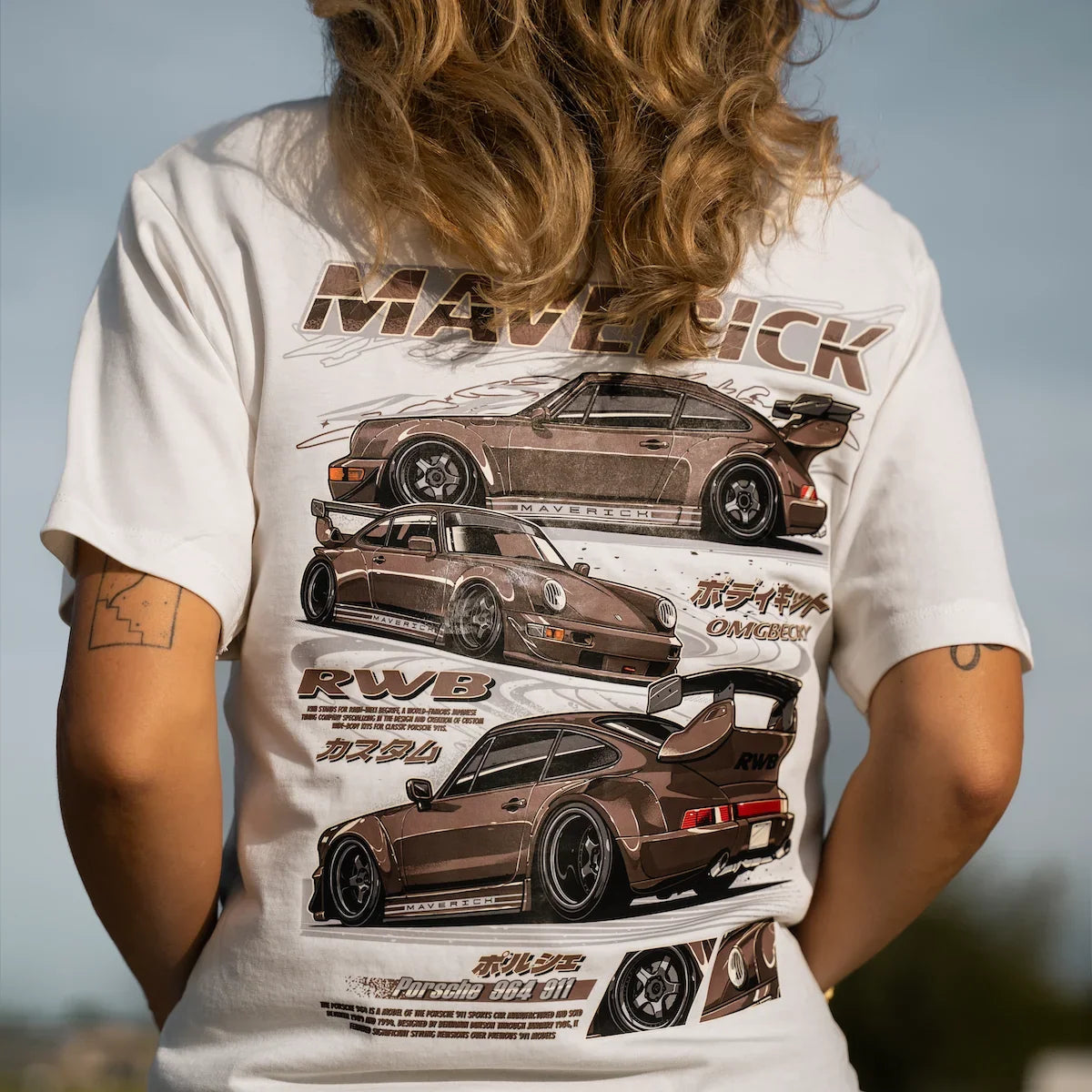 A person viewed from behind wearing a white graphic T-shirt with a large back print featuring three brown sports cars and the word 'MAVERICK'.