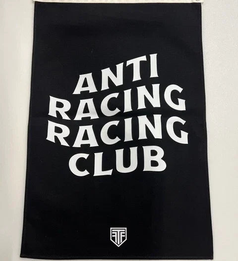 A black rectangular flag with a white hanging sleeve on the left side, featuring the words 'ANTI RACING CLUB' stacked vertically in large white letters and a small white shield logo on the right side.