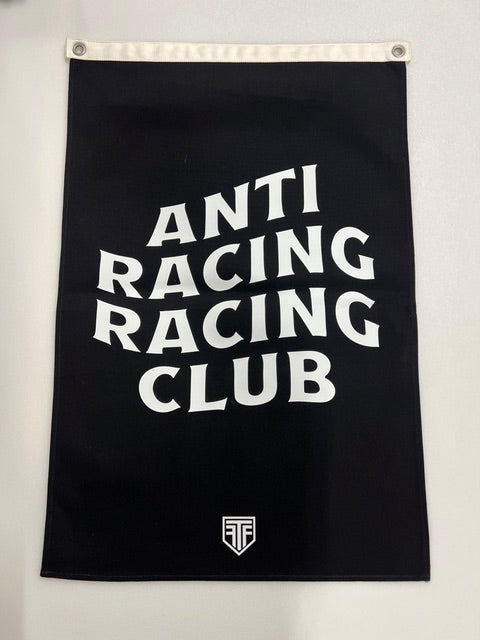 A black rectangular flag with a white hanging sleeve on the left side, featuring the words 'ANTI RACING CLUB' stacked vertically in large white letters and a small white shield logo on the right side.