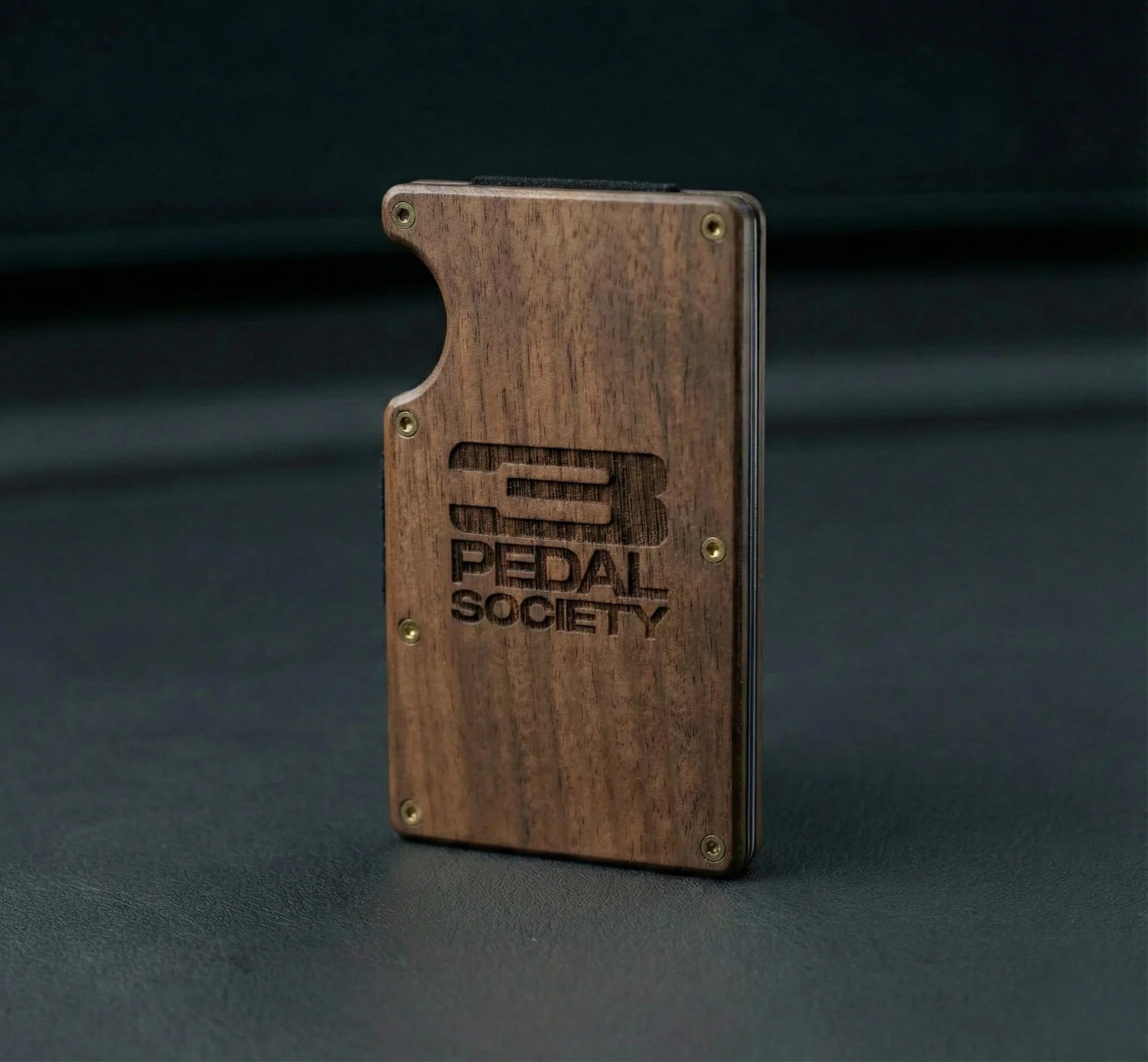 Wooden wallet with '3 Pedal Society' logo on a dark background